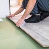 Young worker laying a floor with bright laminated flooring boards